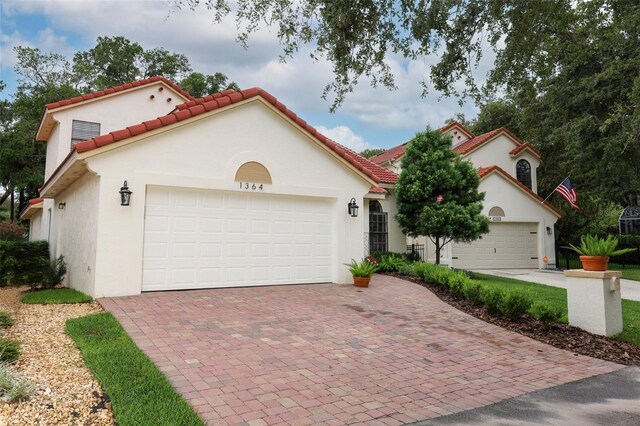 1364 Augusta National Blvd, Winter Springs, FL 32708 - mediterranean / spanish house featuring stucco siding, decorative driveway, a tiled roof, and an attached garage