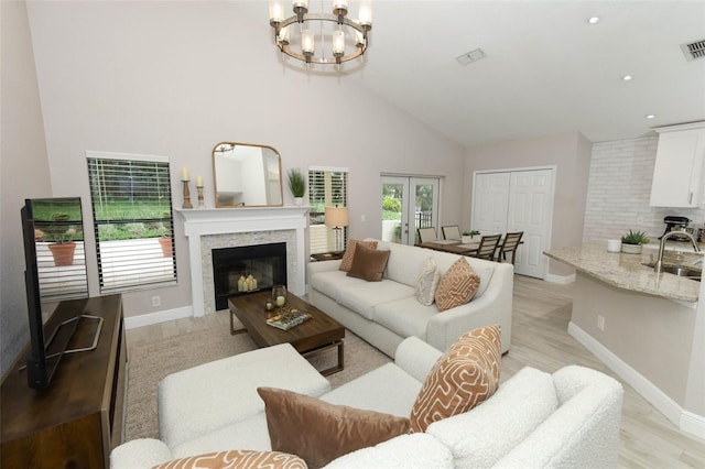 1364 Augusta National Blvd, Winter Springs, FL 32708 - living room featuring light wood-style flooring, a fireplace, a chandelier, high vaulted ceiling, and baseboards
