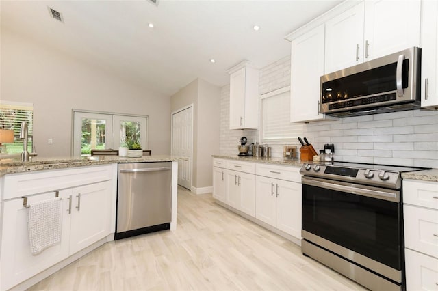 1364 Augusta National Blvd, Winter Springs, FL 32708 - kitchen with appliances with stainless steel finishes, backsplash, lofted ceiling, a sink, and white cabinetry