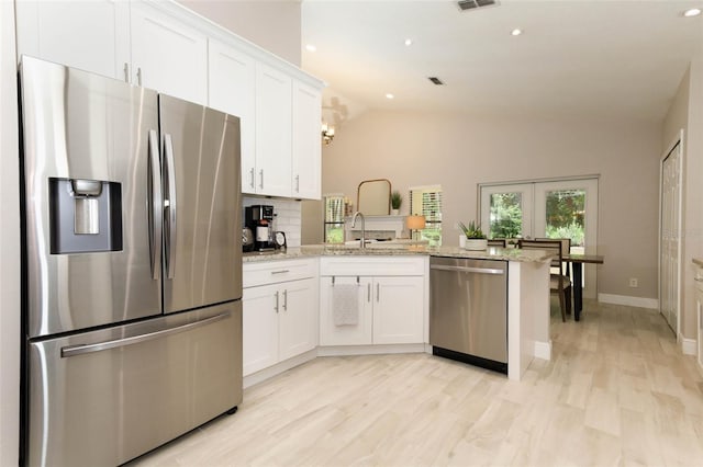 1364 Augusta National Blvd, Winter Springs, FL 32708 - kitchen featuring stainless steel appliances, lofted ceiling, a peninsula, white cabinetry, and light stone countertops