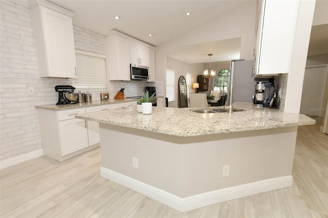 1364 Augusta National Blvd, Winter Springs, FL 32708 - kitchen featuring stainless steel microwave, white cabinetry, a peninsula, light stone counters, and lofted ceiling