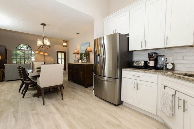 1364 Augusta National Blvd, Winter Springs, FL 32708 - kitchen with stainless steel fridge, backsplash, a chandelier, white cabinets, and decorative light fixtures