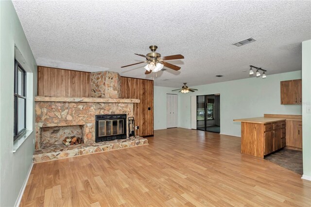 6421 NW 61st St, Ocala, FL 34482 - unfurnished living room with wood finished floors, ceiling fan, a textured ceiling, and a stone fireplace