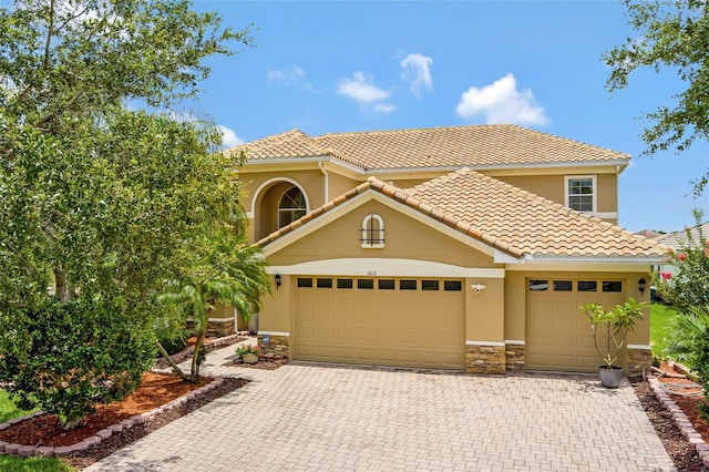 2631 Captains Ct, Kissimmee, FL 34746 - mediterranean / spanish house featuring decorative driveway, stucco siding, stone siding, and a tiled roof