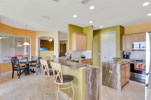 2631 Captains Ct, Kissimmee, FL 34746 - kitchen featuring stainless steel appliances, light brown cabinets, decorative backsplash, light stone countertops, and recessed lighting