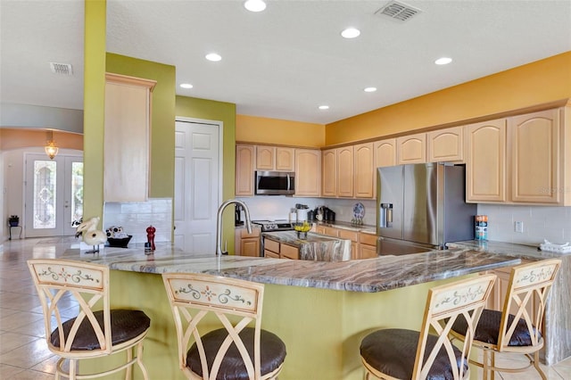 2631 Captains Ct, Kissimmee, FL 34746 - kitchen with stainless steel appliances, light brown cabinetry, a peninsula, decorative backsplash, and recessed lighting