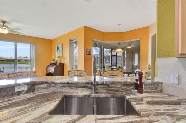 2631 Captains Ct, Kissimmee, FL 34746 - kitchen featuring ceiling fan, light stone countertops, and pendant lighting