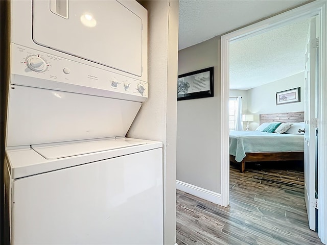 3944 Atrium Dr Unit 4, Orlando, FL 32822 - washroom featuring stacked washing machine and dryer, a textured ceiling, light wood-style floors, and baseboards