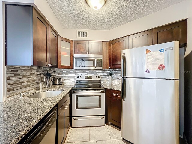 3944 Atrium Dr Unit 4, Orlando, FL 32822 - kitchen featuring stainless steel appliances, a sink, light stone counters, a textured ceiling, and glass insert cabinets