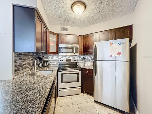 3944 Atrium Dr Unit 4, Orlando, FL 32822 - kitchen with stainless steel appliances, a sink, dark stone counters, tasteful backsplash, and a textured ceiling