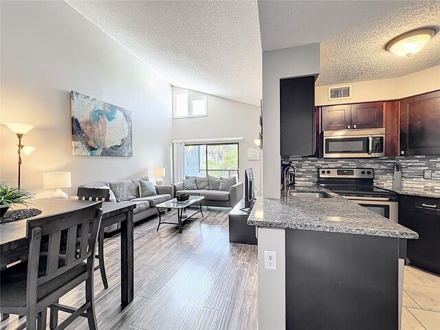 3944 Atrium Dr Unit 4, Orlando, FL 32822 - kitchen featuring stainless steel appliances, a sink, decorative backsplash, stone counters, and a peninsula