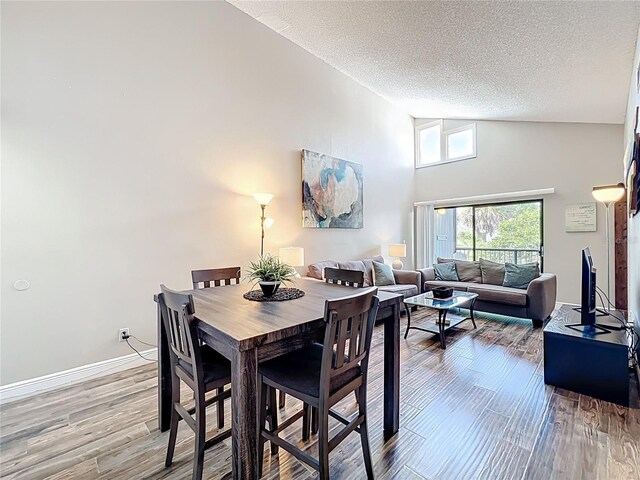 3944 Atrium Dr Unit 4, Orlando, FL 32822 - dining area featuring a textured ceiling, wood finished floors, high vaulted ceiling, and baseboards