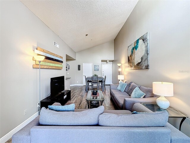 3944 Atrium Dr Unit 4, Orlando, FL 32822 - living room featuring a textured ceiling, vaulted ceiling, baseboards, and wood finished floors
