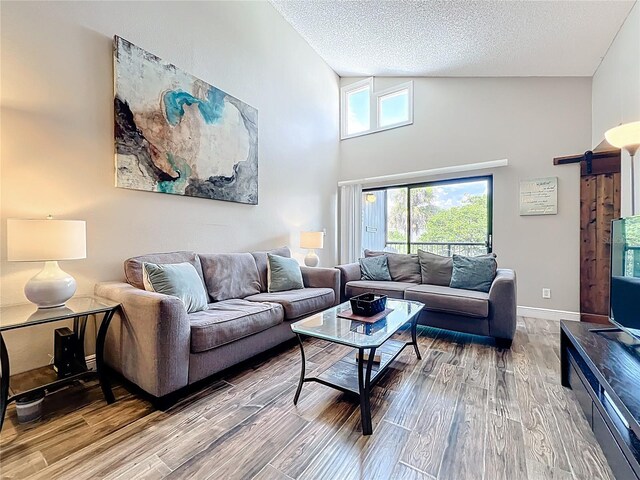 3944 Atrium Dr Unit 4, Orlando, FL 32822 - living room with a barn door, wood finished floors, a textured ceiling, high vaulted ceiling, and baseboards