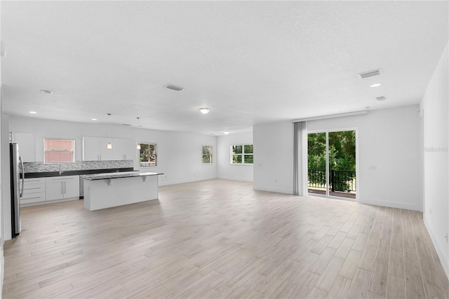 1812 Stoneywood Way, Apopka, FL 32712 - unfurnished living room with baseboards, light wood-type flooring, recessed lighting, a sink, and a textured ceiling