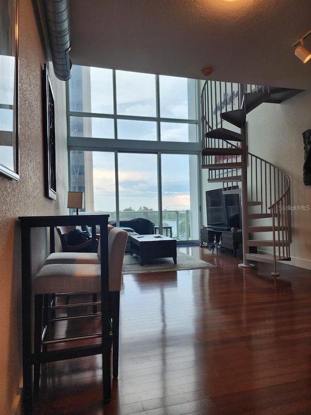 150 E Robinson St Unit 419, Orlando, FL 32801 - living room featuring hardwood / wood-style flooring, stairway, expansive windows, a textured wall, and a towering ceiling