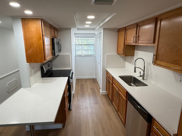 118 S Halifax Ave Unit 409, Daytona Beach, FL 32118 - kitchen featuring appliances with stainless steel finishes, a sink, light wood-style floors, brown cabinets, and recessed lighting