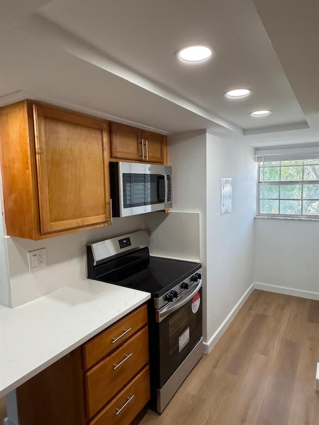 118 S Halifax Ave Unit 409, Daytona Beach, FL 32118 - kitchen with appliances with stainless steel finishes, brown cabinets, light wood-style floors, baseboards, and recessed lighting