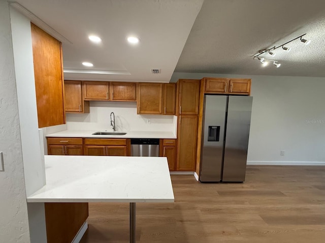 118 S Halifax Ave Unit 409, Daytona Beach, FL 32118 - kitchen featuring stainless steel appliances, a sink, brown cabinets, light wood-style flooring, and light countertops