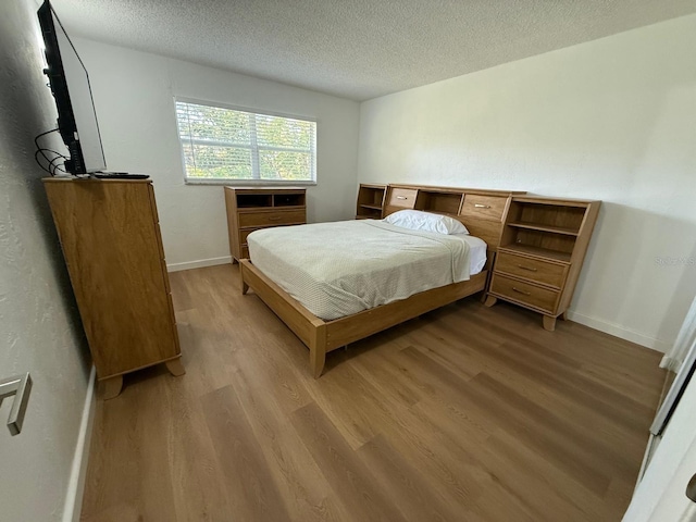 118 S Halifax Ave Unit 409, Daytona Beach, FL 32118 - bedroom featuring light wood-style flooring, a textured ceiling, and baseboards