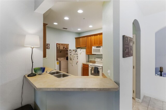 3000 Laurel Park Ln Unit 308, Kissimmee, FL 34741 - kitchen featuring white appliances, a sink, independent washer and dryer, brown cabinets, and arched walkways