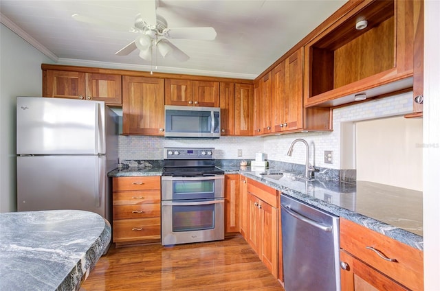 2615 NE 3rd Ct Unit 416, Boynton Beach, FL 33435 - kitchen featuring appliances with stainless steel finishes, a sink, dark stone counters, brown cabinets, and crown molding
