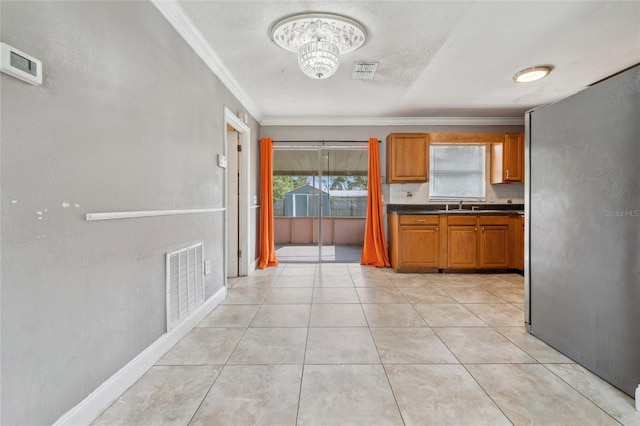 510 Peach Tree Ln, Altamonte Springs, FL 32701 - kitchen featuring freestanding refrigerator, crown molding, brown cabinets, dark countertops, and light tile patterned flooring