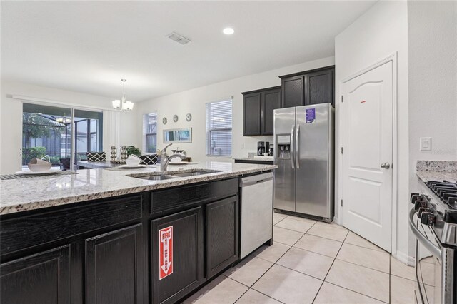 7033 Oakwood St, Davenport, FL 33837 - kitchen featuring appliances with stainless steel finishes, a sink, dark cabinets, a chandelier, and light stone counters