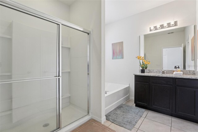 7033 Oakwood St, Davenport, FL 33837 - bathroom featuring vanity, tile patterned flooring, a stall shower, a bath, and baseboards