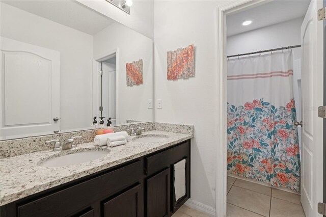 7033 Oakwood St, Davenport, FL 33837 - full bath featuring tile patterned flooring, double vanity, curtained shower, and baseboards