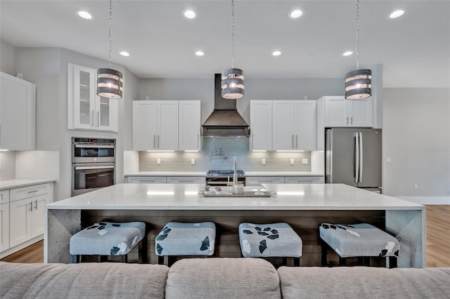 2459 Mcgregor Oaks Ln, Deland, FL 32720 - kitchen featuring stainless steel appliances, custom exhaust hood, a kitchen bar, light wood-type flooring, and recessed lighting