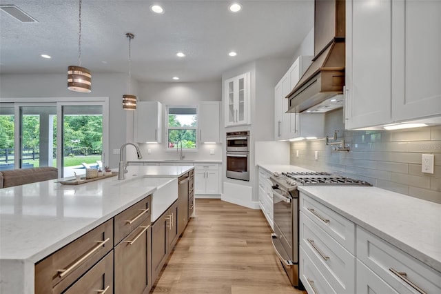 2459 Mcgregor Oaks Ln, Deland, FL 32720 - kitchen with appliances with stainless steel finishes, a sink, light wood finished floors, wall chimney exhaust hood, and recessed lighting
