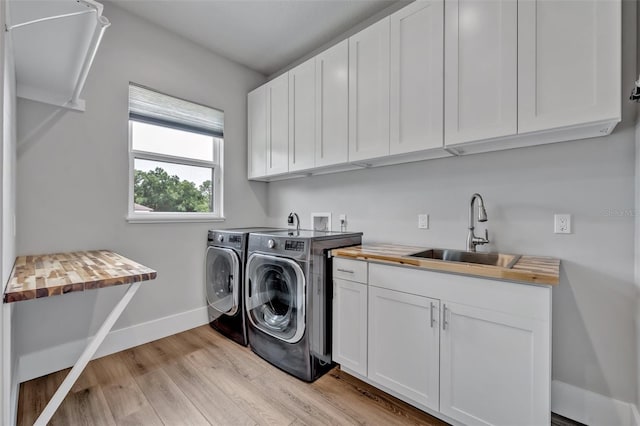 2459 Mcgregor Oaks Ln, Deland, FL 32720 - laundry area featuring washing machine and clothes dryer, cabinet space, light wood-style flooring, and baseboards