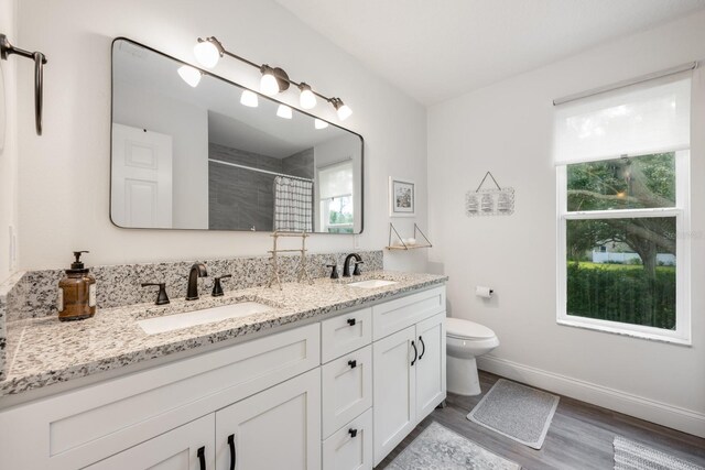 10241 Pointview Ct, Orlando, FL 32836 - bathroom with double vanity, tiled shower, toilet, wood finished floors, and baseboards
