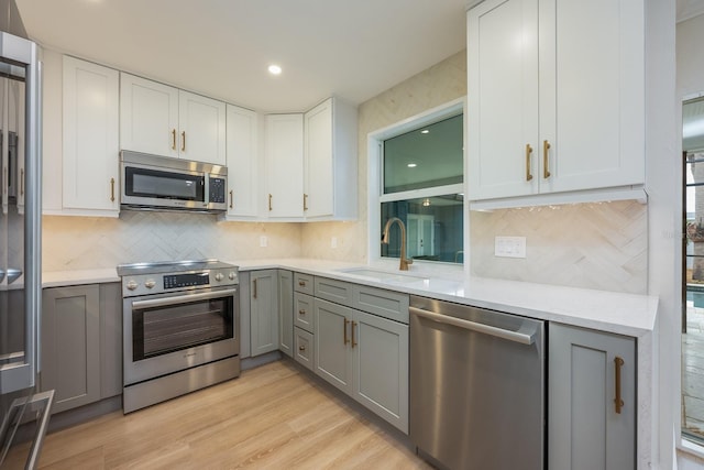 5108 Saint Albans Ave, Siesta Key, FL 34242 - kitchen with appliances with stainless steel finishes, gray cabinetry, a sink, tasteful backsplash, and light countertops