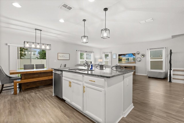 17416 Painted Leaf Way, Clermont, FL 34714 - kitchen featuring a sink, dishwasher, dark stone countertops, wood finished floors, and a center island with sink