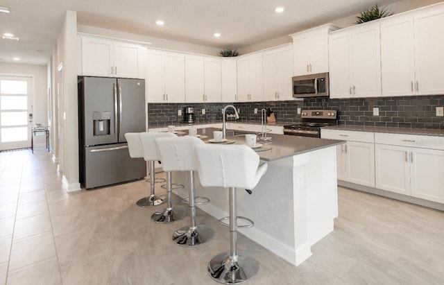 8986 Cabot Cliffs Dr, Davenport, FL 33896 - kitchen featuring appliances with stainless steel finishes, decorative backsplash, white cabinetry, an island with sink, and recessed lighting