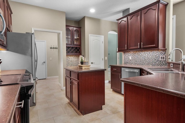 3307 Kentshire Blvd, Ocoee, FL 34761 - kitchen with stainless steel appliances, a sink, dark countertops, arched walkways, and backsplash