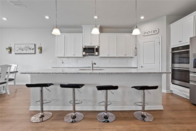 2168 Aibonito Cir, Clermont, FL 34711 - kitchen with stainless steel appliances, backsplash, white cabinets, a kitchen bar, and light stone countertops