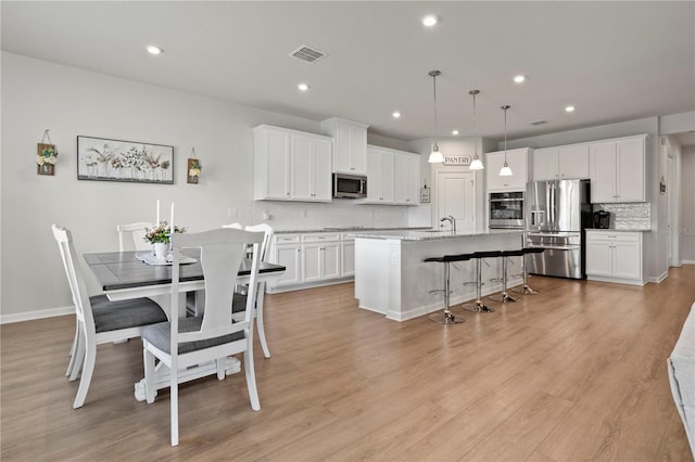 2168 Aibonito Cir, Clermont, FL 34711 - kitchen with appliances with stainless steel finishes, tasteful backsplash, white cabinetry, a breakfast bar area, and an island with sink