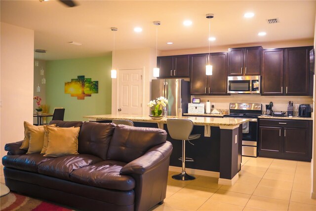 130 Claire Ln, Davenport, FL 33837 - kitchen featuring appliances with stainless steel finishes, open floor plan, a breakfast bar, light tile patterned floors, and tasteful backsplash