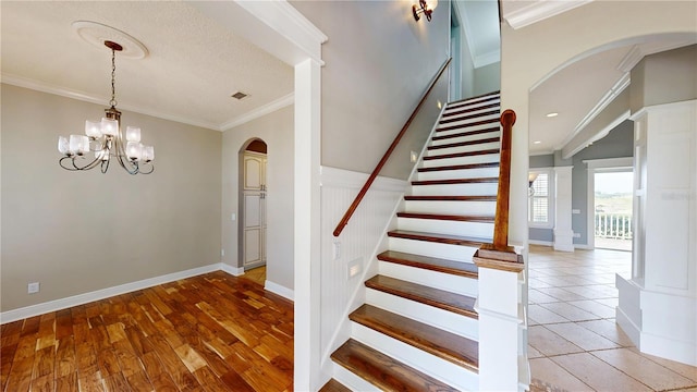 10809 Arrowtree Blvd, Clermont, FL 34715 - stairway with arched walkways, ornamental molding, a chandelier, baseboards, and wood finished floors