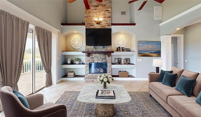10809 Arrowtree Blvd, Clermont, FL 34715 - tiled living area with ceiling fan, a towering ceiling, built in shelves, a stone fireplace, and baseboards