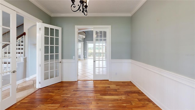10809 Arrowtree Blvd, Clermont, FL 34715 - unfurnished dining area featuring french doors, wood finished floors, a wainscoted wall, crown molding, and a chandelier