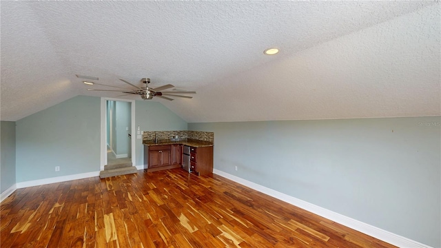 10809 Arrowtree Blvd, Clermont, FL 34715 - additional living space with a textured ceiling, dark wood finished floors, baseboards, ceiling fan, and vaulted ceiling
