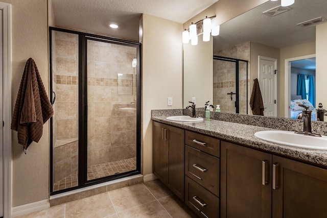 5416 Tessin Trl, Saint Cloud, FL 34771 - full bathroom featuring a shower stall, double vanity, baseboards, tile patterned flooring, and a textured ceiling