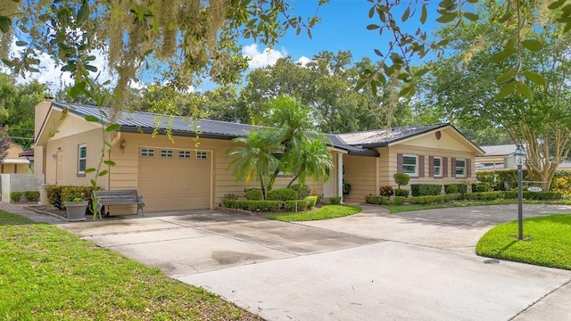 3405 Werber St, Orlando, FL 32806 - ranch-style home with concrete driveway, an attached garage, a chimney, metal roof, and a standing seam roof