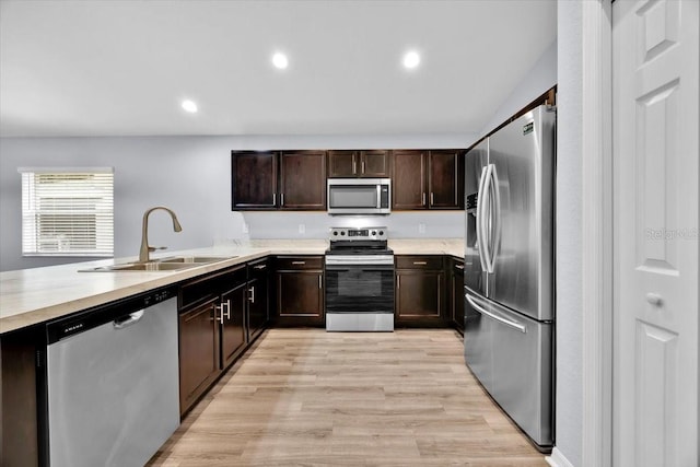 907 Pearly Ridge Ln, Lakeland, FL 33809 - kitchen with appliances with stainless steel finishes, a sink, light countertops, dark brown cabinets, and light wood-style floors