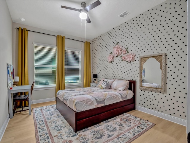 8047 Chilton Dr, Orlando, FL 32836 - bedroom with wallpapered walls, wood finished floors, baseboards, a ceiling fan, and an accent wall