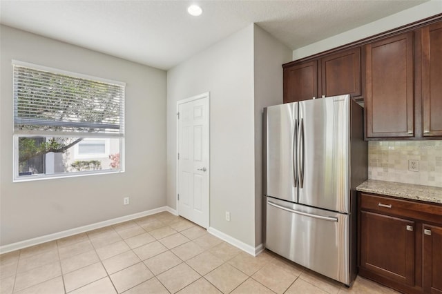 10124 Westpark Preserve Blvd, Tampa, FL 33625 - kitchen featuring freestanding refrigerator, baseboards, light tile patterned floors, backsplash, and light stone countertops